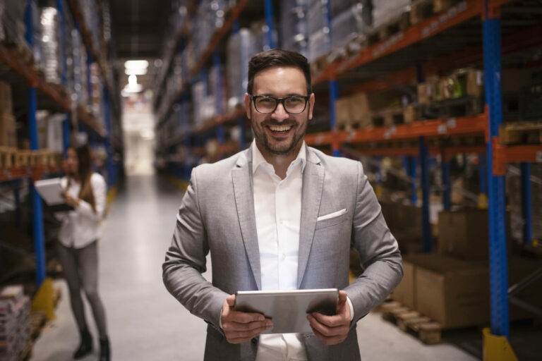 cheerful successful middle aged manager businessman holding tablet computer large warehouse organizing distribution
