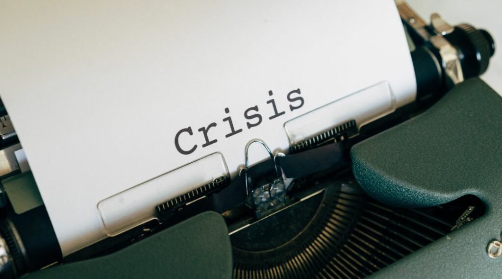 Entwicklung einer Unternehmenskrise, hier Schreibmaschine mit Papiereinzug und dem Wort "crisis"