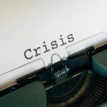 Entwicklung einer Unternehmenskrise, hier Schreibmaschine mit Papiereinzug und dem Wort "crisis"